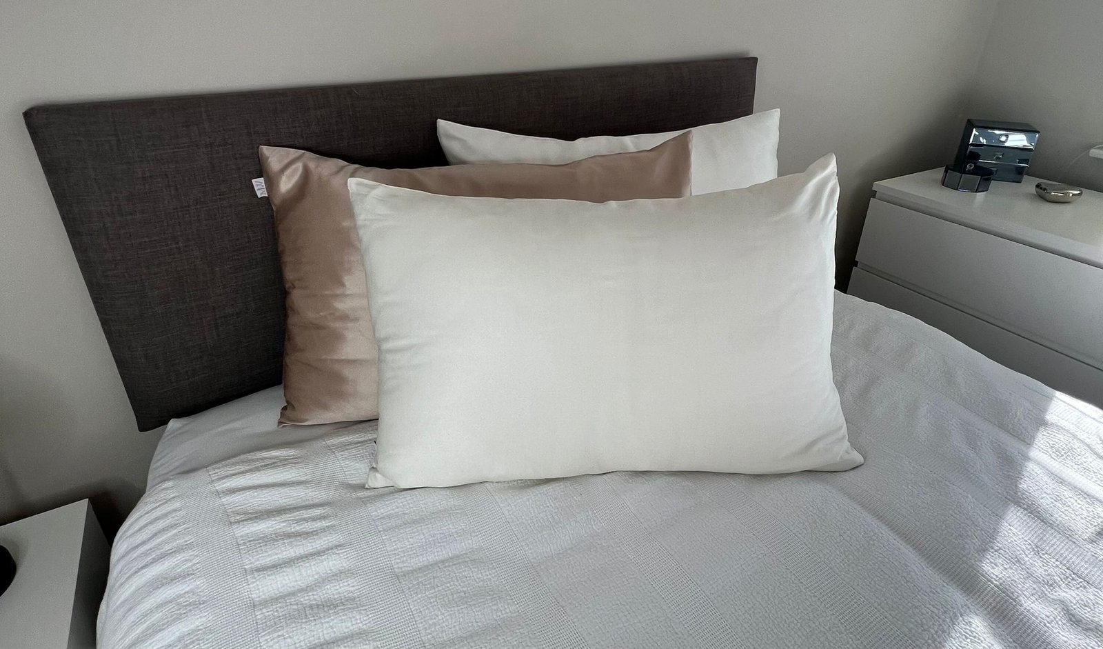 A cream silk pillowcase on a made bed
